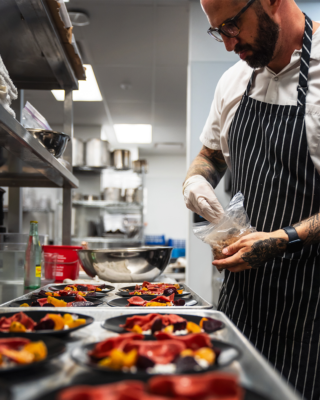 Professional chef plating food in a busy commercial kitchen